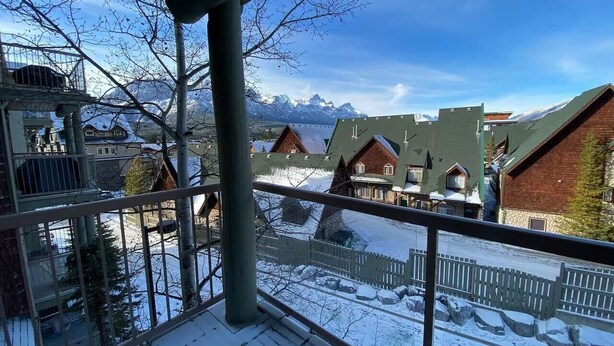 Ein Balkon mit Blick auf verschneite Landschaft und Häuser, einem Metallgeländer und einem klaren Himmel.