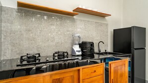 A modern kitchen with a black refrigerator, a coffee maker, and a blender on the counter. - Bugenvil Villa Ubud (Kabupaten Gianyar)