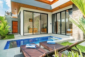 A modern house with a swimming pool, outdoor furniture, and a stone wall. - Bugenvil Villa Ubud (Kabupaten Gianyar)