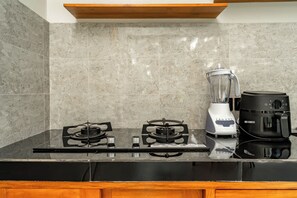 A kitchen with a gas stove, a blender, and a coffee maker on a black countertop. - Bugenvil Villa Ubud (Kabupaten Gianyar)