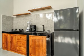 Eine moderne Küche mit einem schwarzen Kühlschrank, Holzschränken, einer Kaffeemaschine und einem Mixer.