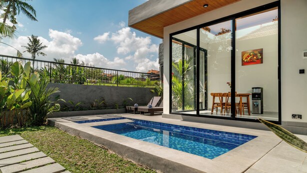 A modern outdoor swimming pool with lounge chairs and a dining area. - Bugenvil Villa Ubud (Kabupaten Gianyar)