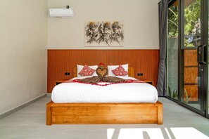 Ein Schlafzimmer mit einem Holz-Kopfteil, einem Bett mit weißer Bettwäsche, roten und weißen Kissen und einer Wand-Klimaanlage.