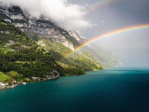 A coastal landscape with a mountain, a lake, and a rainbow.