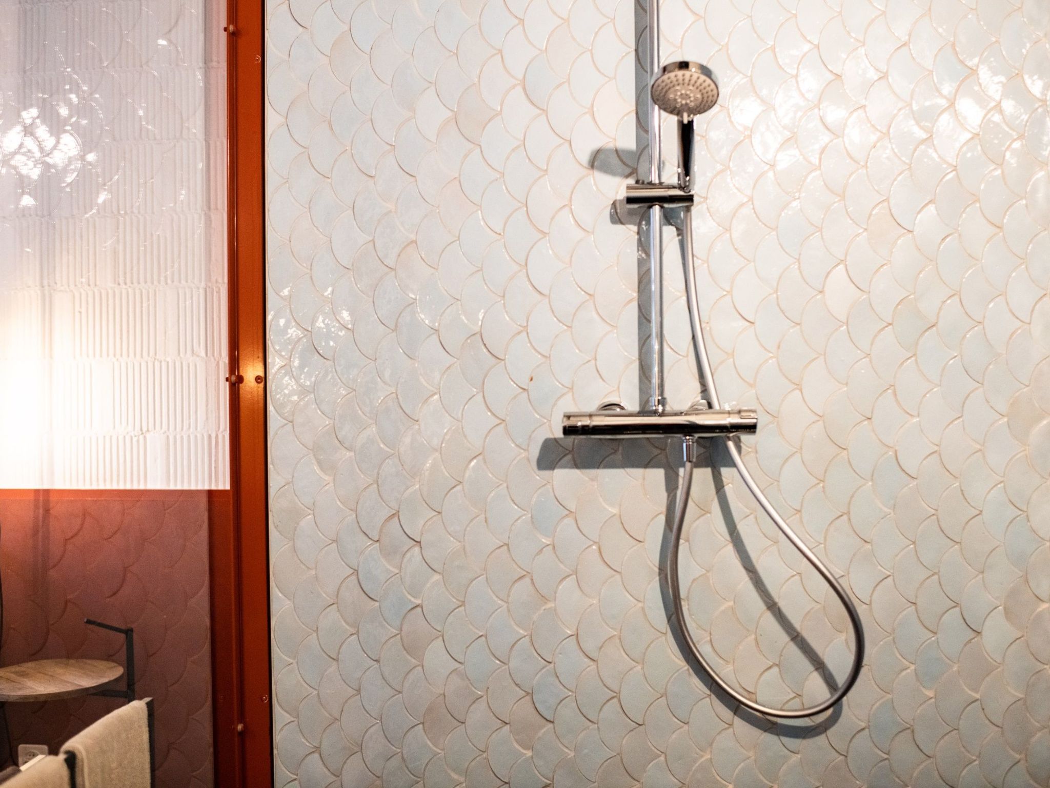 Une douche au design moderne, dotée d’une poignée métallique et d’un flexible incurvé.