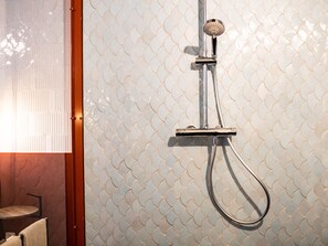 A shower with a modern design, featuring a metallic handle and a curved hose.