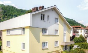 Ein mehrstöckiges Wohngebäude mit flachem Dach, zahlreichen Fenstern und einem Balkon.