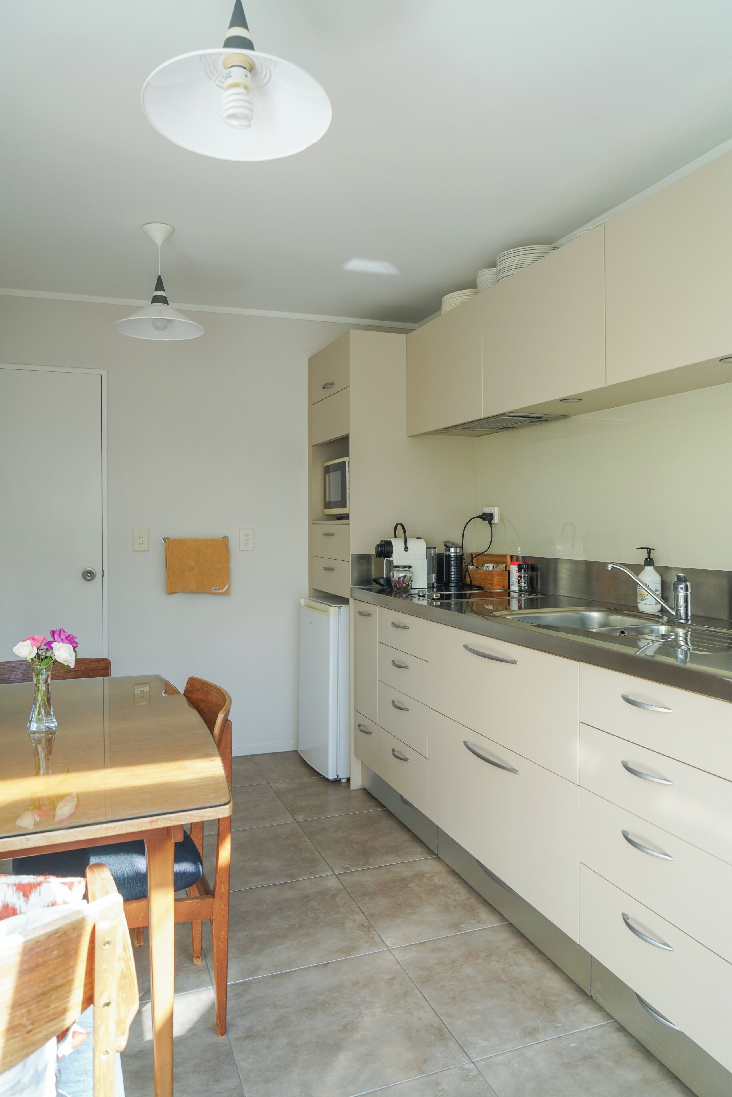 A kitchen with a dining table, chairs, a refrigerator, and a microwave.