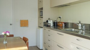 A kitchen with a dining table, chairs, a refrigerator, and a microwave. - Private, spacious, well appointed, self-contained unit. (Tauranga)