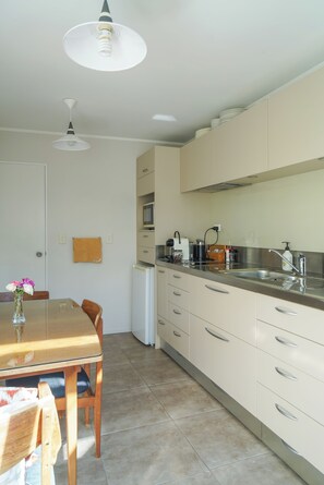 Eine Küche mit Esstisch, Stühlen, Kühlschrank und Mikrowelle.