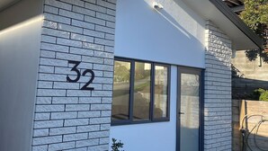 A modern building with a brick facade, a large window, and a red planter with a plant. - Private, spacious, well appointed, self-contained unit. (Tauranga)