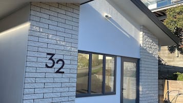 Un bâtiment moderne avec une façade en briques, une grande fenêtre et un jardinier rouge contenant une plante.