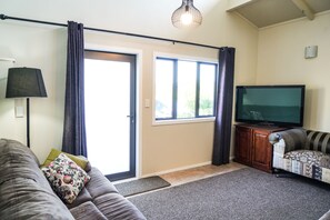 A living room with a sofa, a television, a lamp, and a window with curtains.