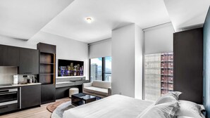 A modern hotel room with a bed, a sofa, a desk, and a large window with a city view. - Miami E11even w Resort Amenities (Miami)