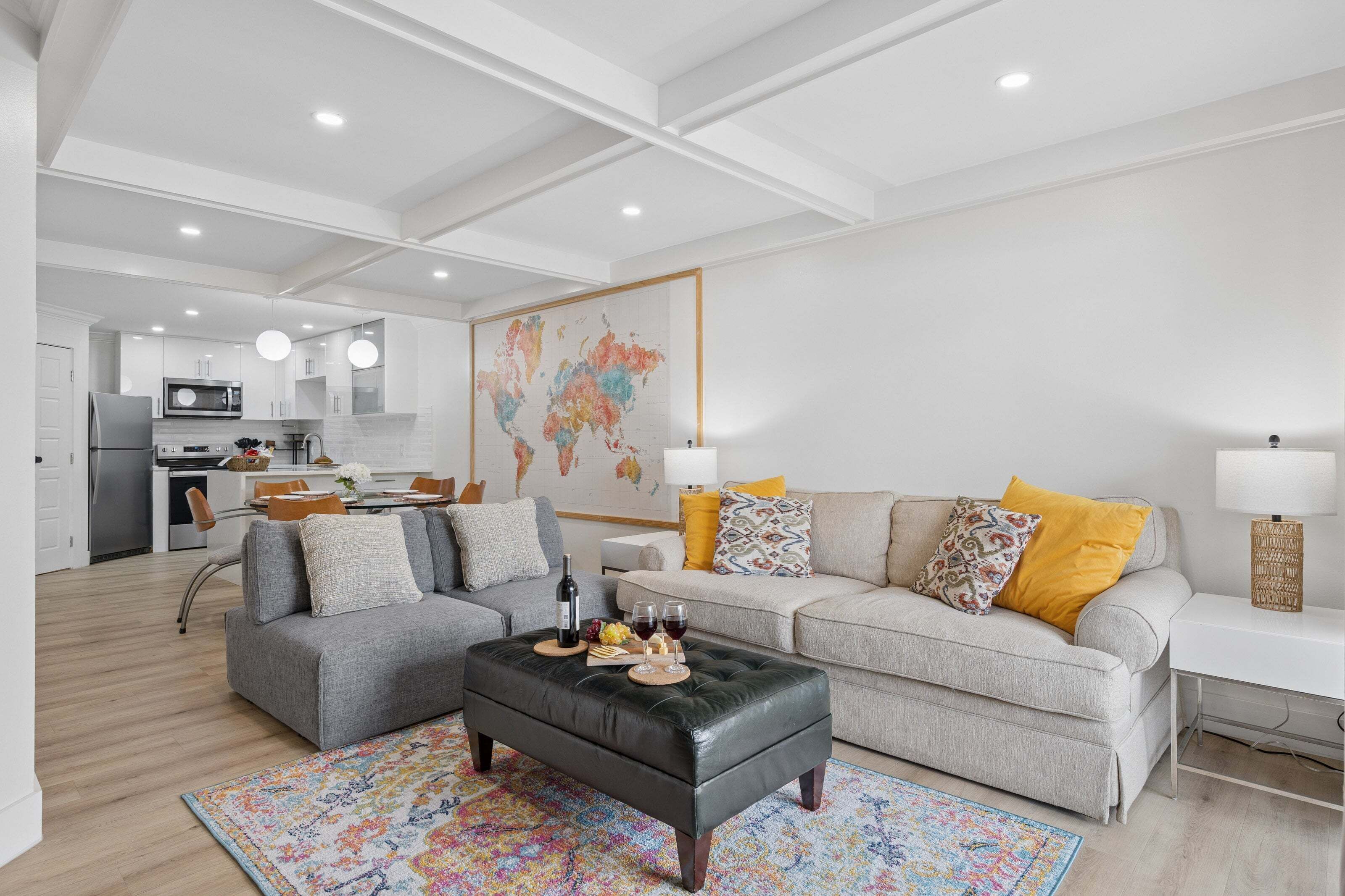 Una sala de estar moderna con un sofá gris, un reposapiés negro y una alfombra colorida.