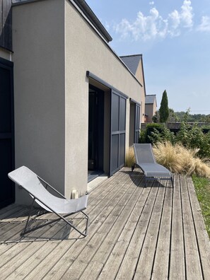 A modern building with a wooden deck, two lounge chairs, and a clear sky. - A 5-minute walk to the beach, quiet house, ideal for families (Saint-Lunaire)