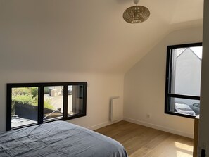 A bedroom with a bed, a radiator, and a window overlooking a garden. - A 5-minute walk to the beach, quiet house, ideal for families (Saint-Lunaire)