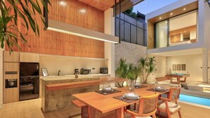 A modern kitchen with wooden cabinetry, a built-in island, and a dining area with a pool table. - Casa Cemagi - Luxury 3BR Villa Near Beach by Orivista (Kecamatan Mengwi)