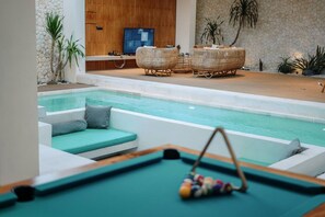 Ein Poolbereich mit Liegestuhl und Fernseher im Hintergrund.