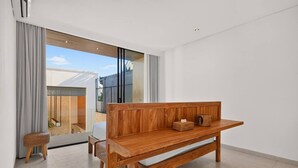 A modern living room with a wooden bench, a small stool, and a glass door leading to a balcony. - Casa Cemagi - Luxury 3BR Villa Near Beach by Orivista (Kecamatan Mengwi)