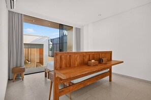 Ein modernes Wohnzimmer mit einer hölzernen Bank, einem kleinen Hocker und einer Glastür, die auf einen Balkon führt.