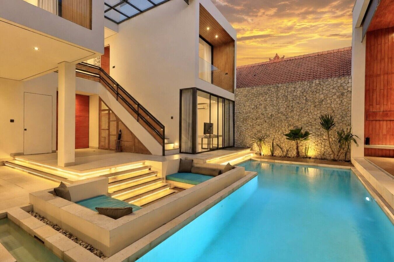 Una casa moderna con piscina, escalera y un muro de piedra.