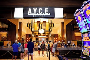 Un área de bufé con un cartel que dice 'A.Y.C.E. BUFFET' y una máquina tragamonedas al frente.