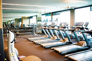 Un gimnasio con cintas de correr, bicicletas estáticas y pesas libres.