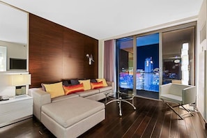 A modern hotel room with a sofa, a glass table, a view of the cityscape, and a wooden accent wall. - Palms Place Hotel  (Las Vegas)