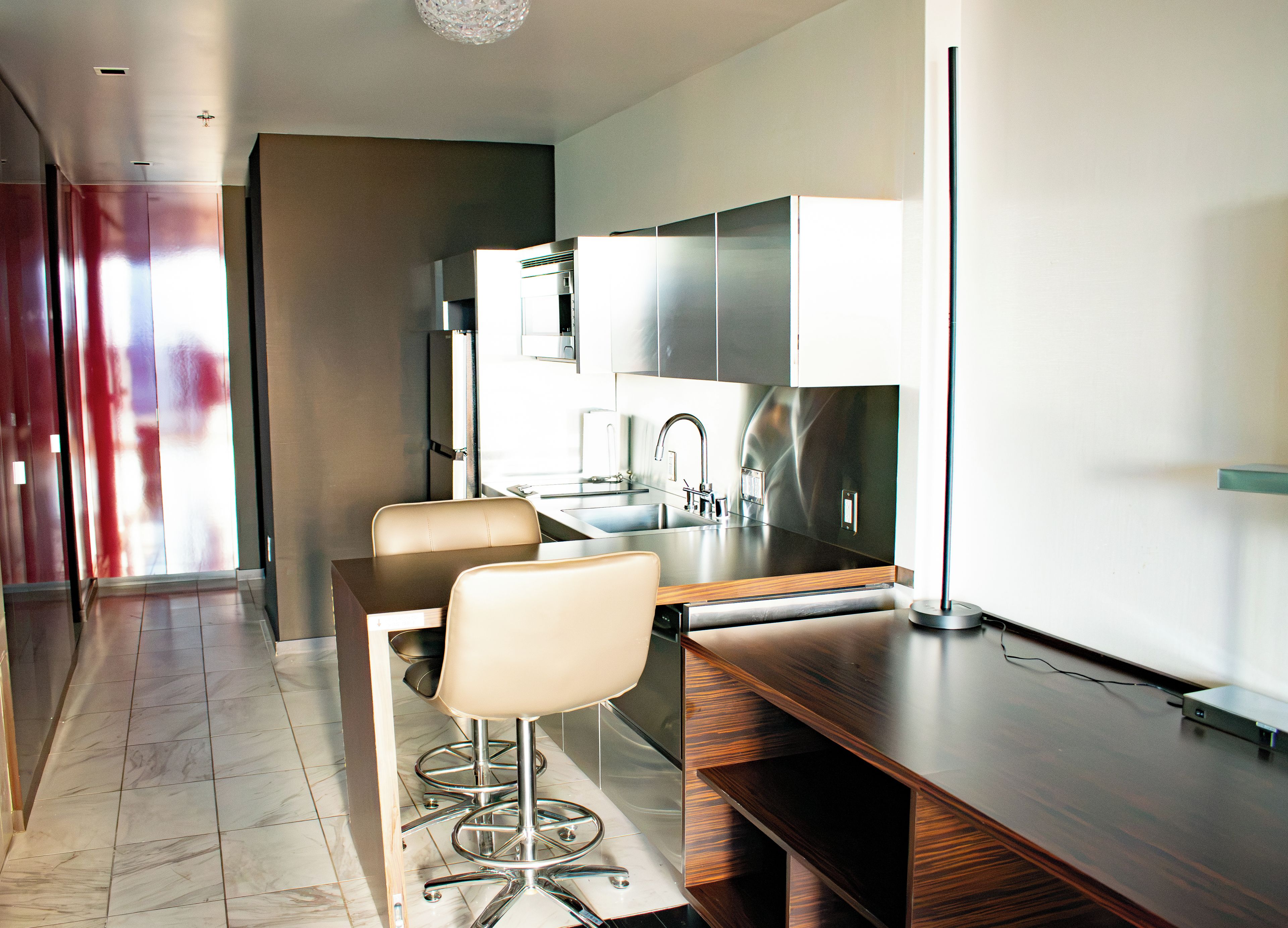 A modern kitchen with a dining area, including a bar stool and a table.