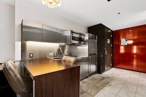 A modern kitchen with stainless steel appliances, a wooden dining table, and a red accent wall. - Palms Place Hotel  (Las Vegas)