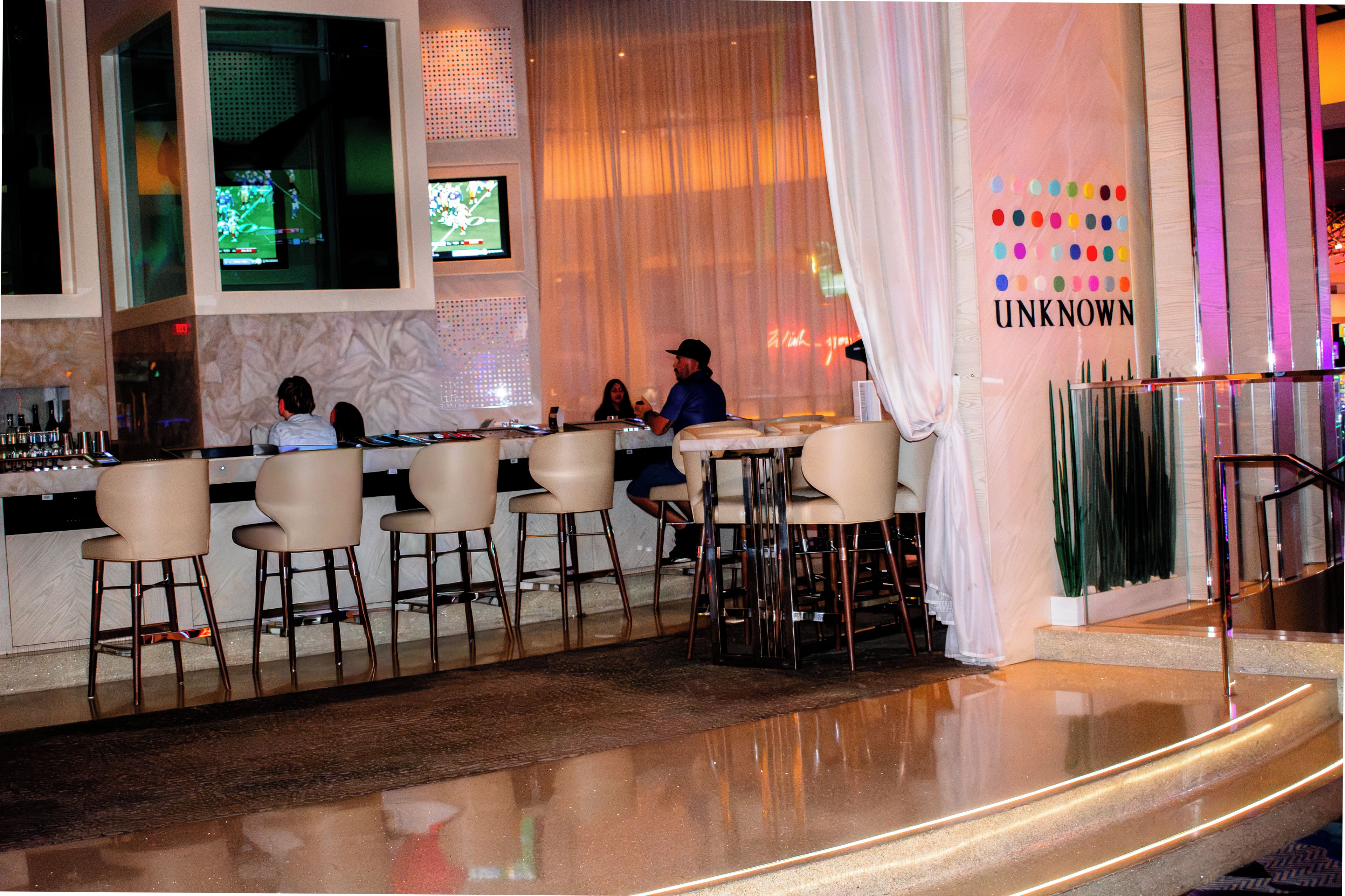 A bar area with seating and a television screen displaying a sports game.