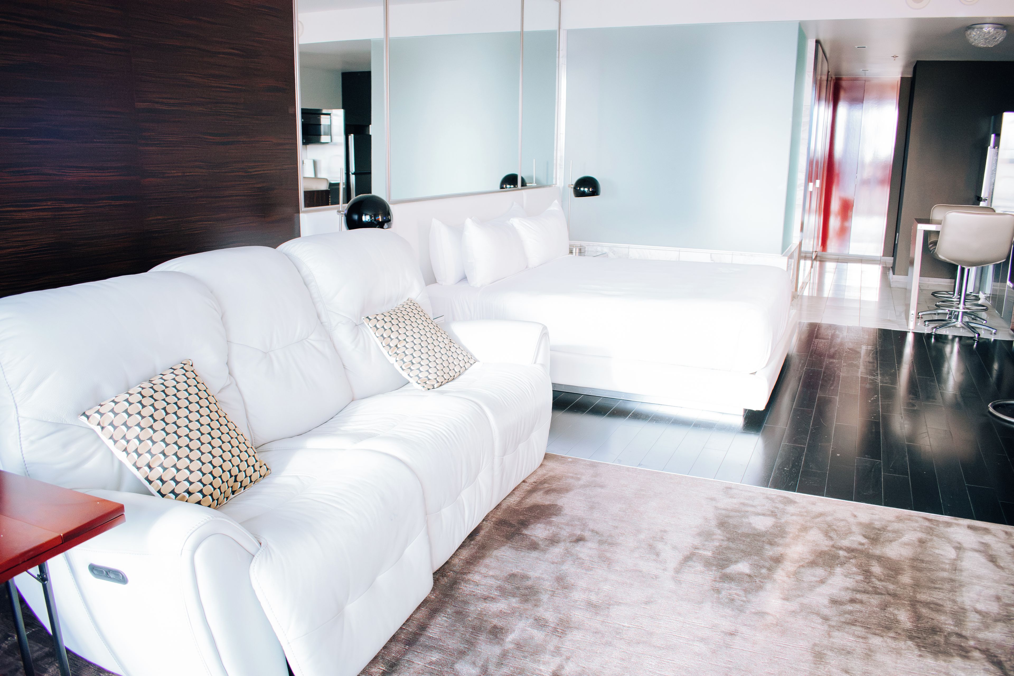 A modern living room with a white sofa, a patterned throw pillow, and a large mirror.