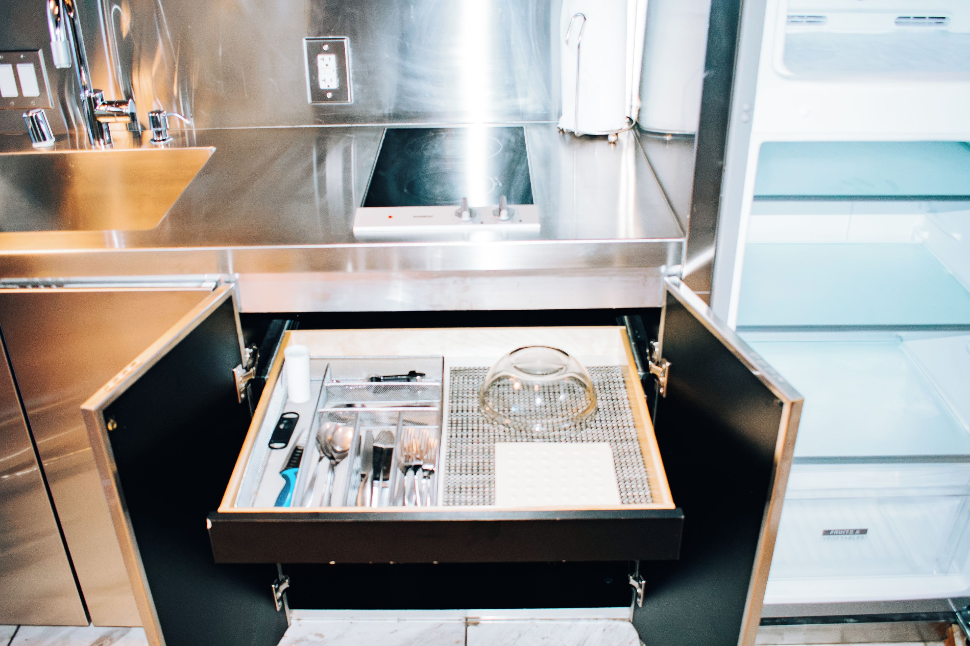 A kitchen drawer with utensils and a tea kettle.