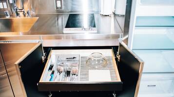 A kitchen drawer with utensils and a tea kettle.