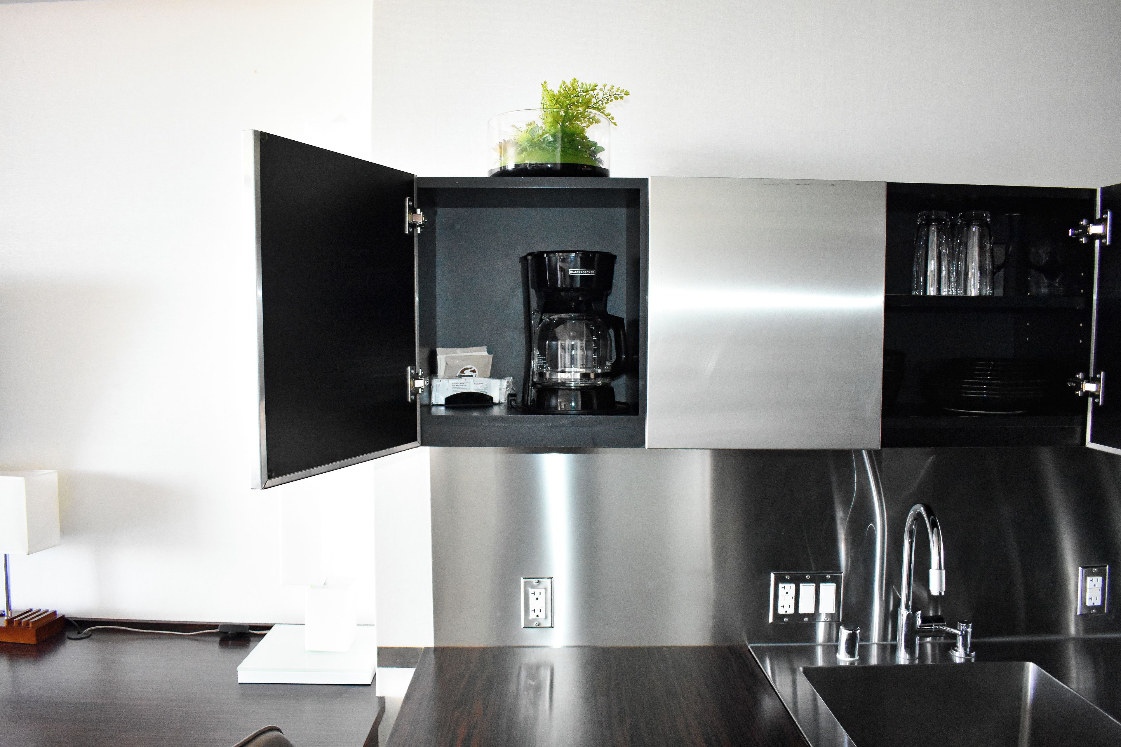 A modern kitchen with a built-in coffee maker and a glass-fronted cabinet.