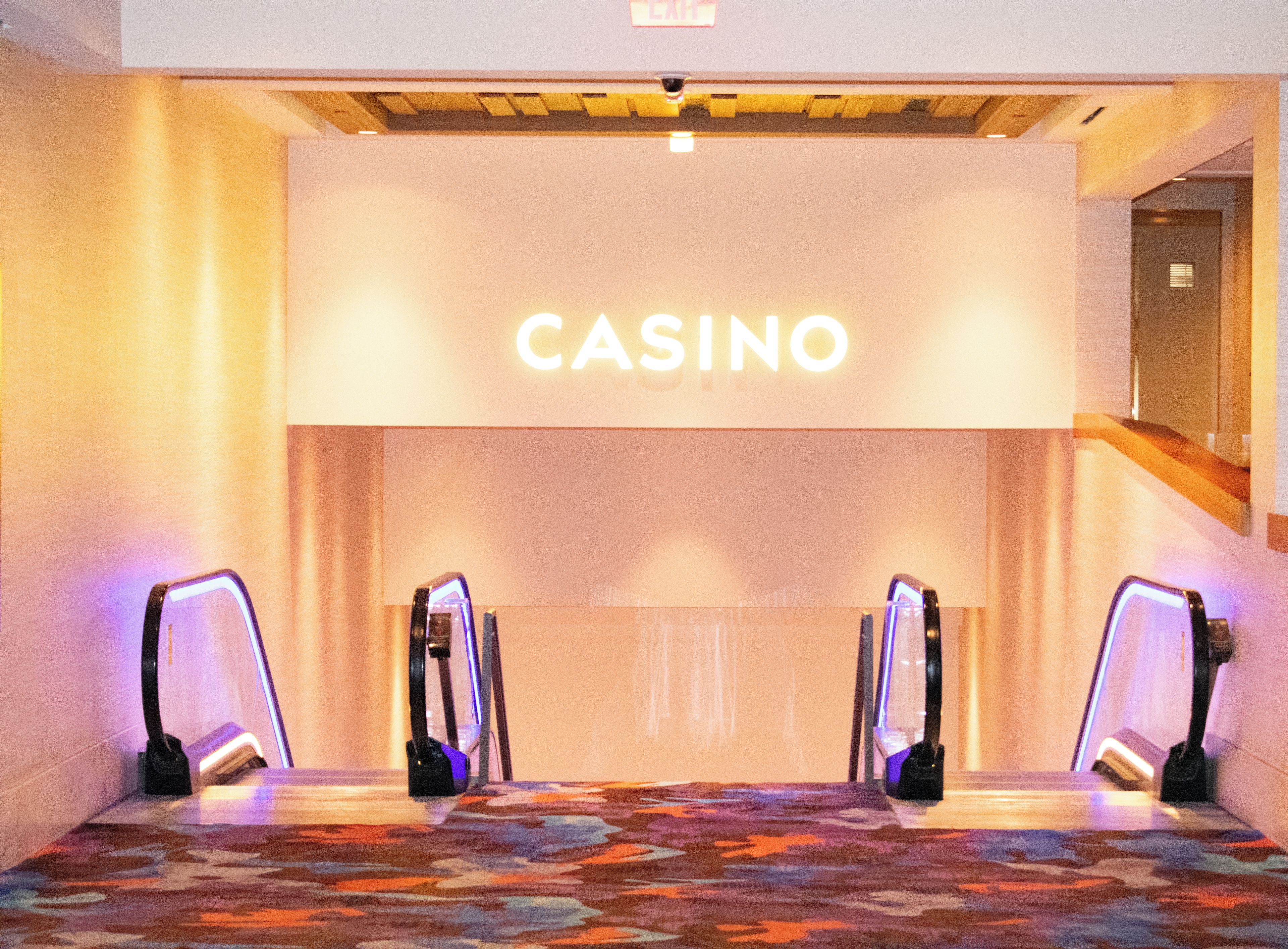 A hotel lobby with a 'CASINO' sign, a patterned carpet, and two illuminated signs on either side.