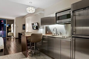 A modern kitchen with stainless steel appliances, a bar area, and a seating space.