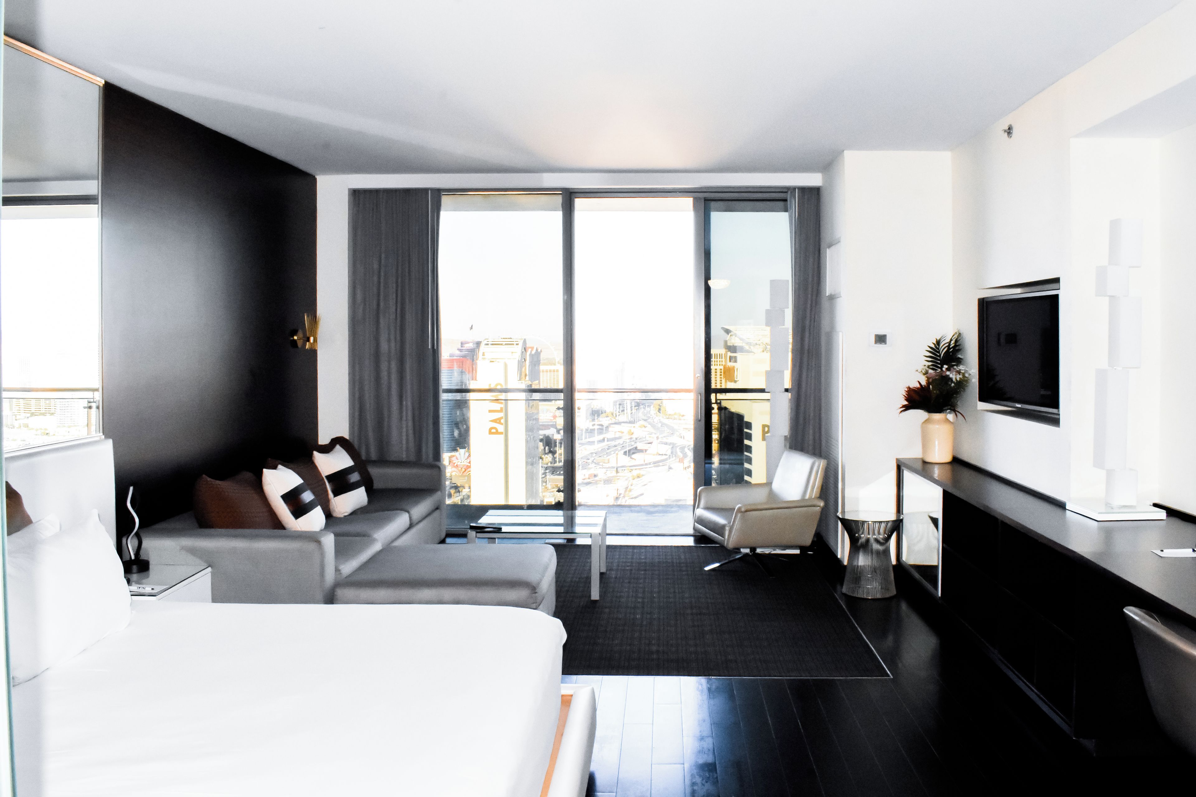 Een moderne hotelkamer met een bed, een bank en een televisie aan de muur.