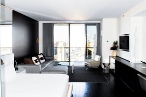 A modern hotel room with a bed, sofa, and a TV on the wall. - LasVegas Suite Rental (Las Vegas)