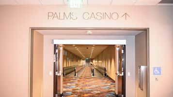 Un couloir dont le sol est recouvert d’une moquette, menant à un panneau indiquant la sortie (« EXIT ») et à un panneau indiquant le « PALMS CASINO », avec une flèche pointant vers le haut.