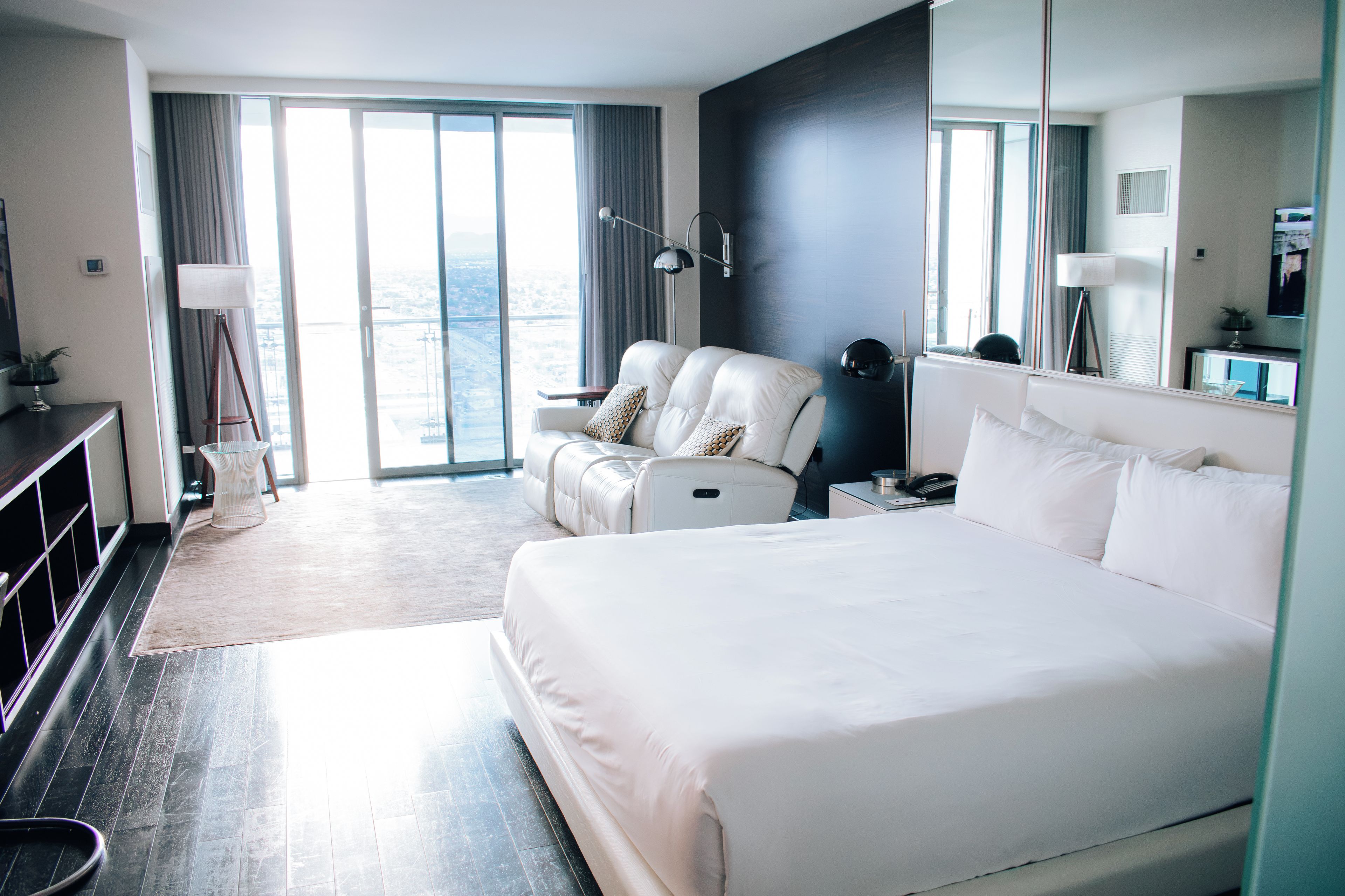 Ein Hotelzimmer mit einem großen Bett, einer Sitzecke mit einem Sessel, einem Schreibtisch und einem großen Fenster mit Aussicht.