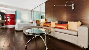 A modern hotel room with a glass coffee table, a sofa with cushions, a red accent wall, and a large mirror. - Palms Place Hotel  (Las Vegas)