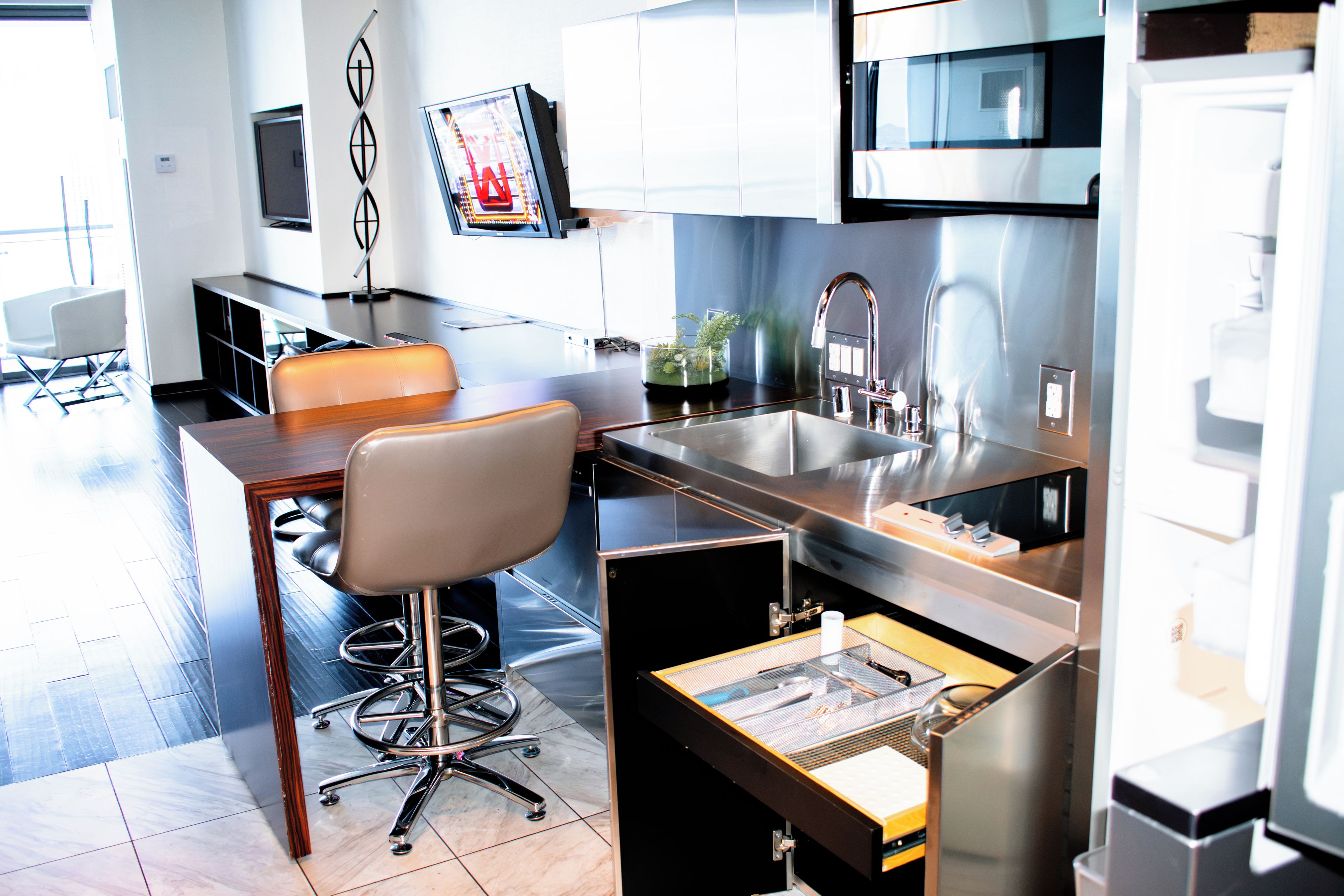 A modern kitchen with a built-in microwave, stainless steel appliances, and a bar area with a chair.