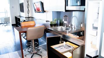 A modern kitchen with a built-in microwave, stainless steel appliances, and a bar area with a chair.