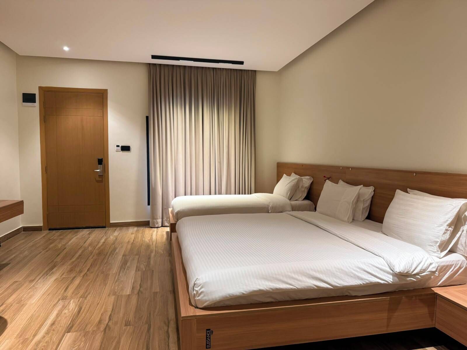 Habitación de hotel con una cama y puerta de madera, además de una cortina.