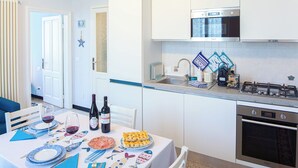 Una cucina moderna con piano cottura a gas, forno e microonde. È presente un tavolo da pranzo apparecchiato con piatti, posate e bottiglie di vino.