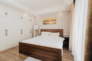 Ein Schlafzimmer mit einem großen Bett, einem Holzkopfende, einem weißen Kleiderschrank und einem Bild an der Wand.