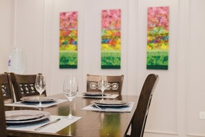 Ein Esszimmer mit Tisch, Geschirr, Besteck und Weingläsern, umgeben von Stühlen.