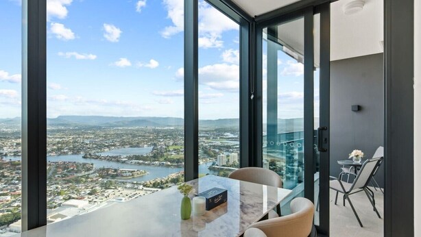 Ein modernes Zimmer mit großem Panoramafenster, einem Marmortisch und Blick auf Stadt und Wasser.